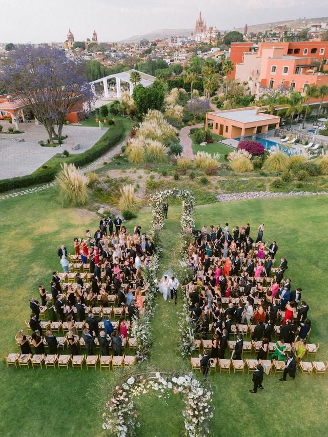 Garden wedding ceremony with wooden chairs and soft pink, lavender and white florals at an Easton Events Mexico wedding.
